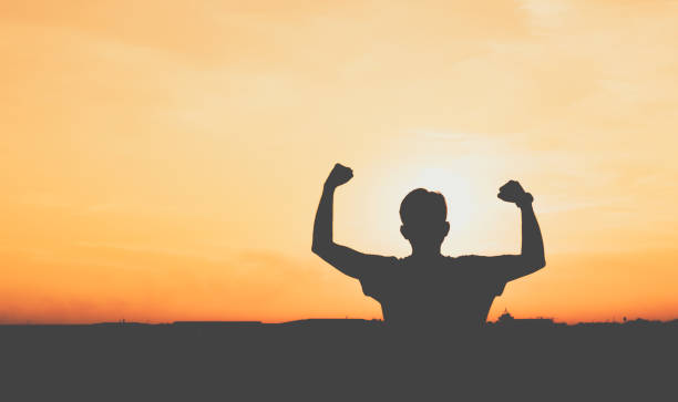 istock Silhouette raised arms man at sunset. 1254497203