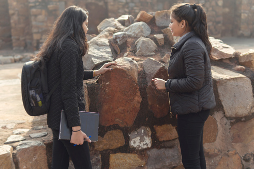 Indian group of college female students collecting information in the old fort and making college project. summer vacations work. outdoor shoot. location is Delhi old fort.