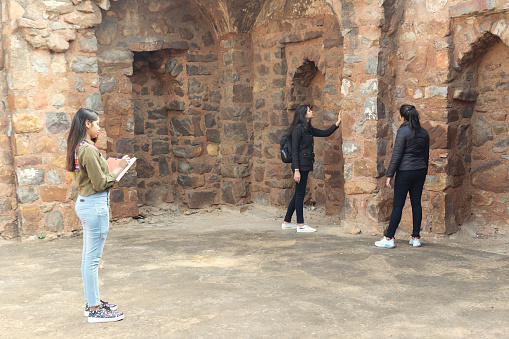 Indian group of college female students collecting information in the old fort and making college project. summer vacations work. outdoor shoot. location is Delhi old fort.