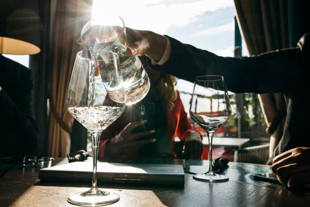 Close up shot of human hand pouring water into the glass in restaurant.