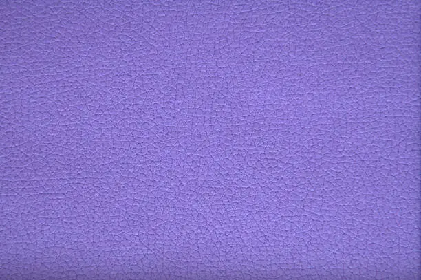 The texture of genuine leather of high-quality workmanship with small veins and folds, artificially painted in bright purple. Background.