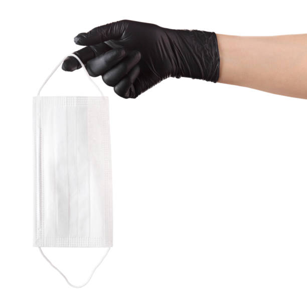 istock Hand in black gloves holding disposable face mask isolated on white background 1254517611
