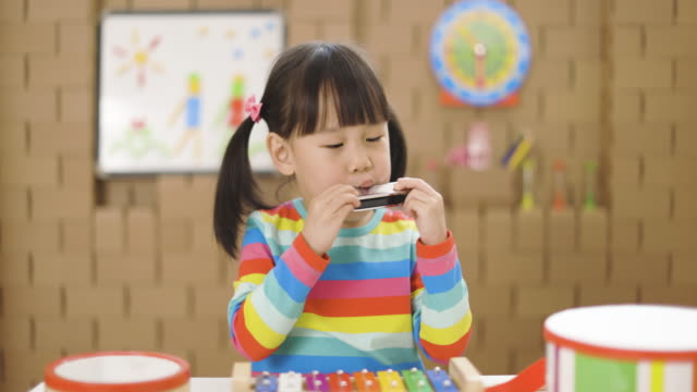 toddler girl play harmonica for home schooling