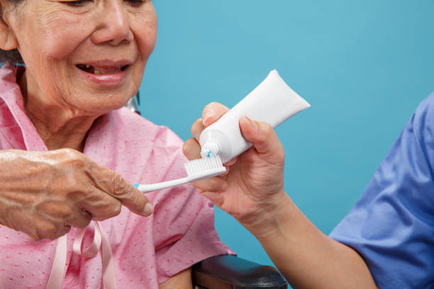 soignant prendre soin femme âgée asiatique tout en utilisant la brosse à dents. - japanese ethnicity women asian and indian ethnicities smiling photos et images de collection