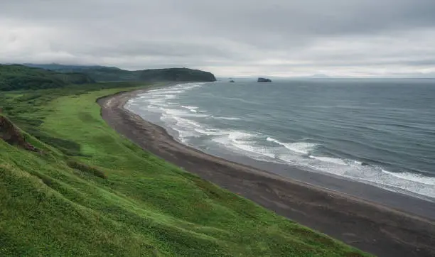 Beach with black sand and Waves in Pacific ocean shore on Kamchatka.