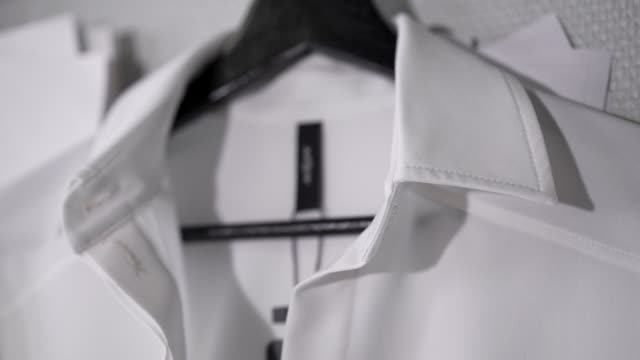 White shirt with black label on black hanger in fashion studio