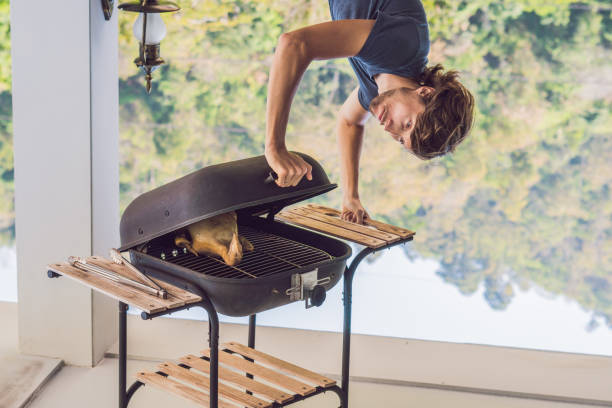 Handsome man preparing barbecue for friends standing upside down.