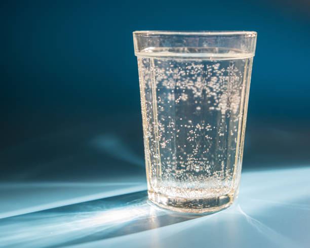 istock glass of water stands on a table lit by sunlight. 1254526466