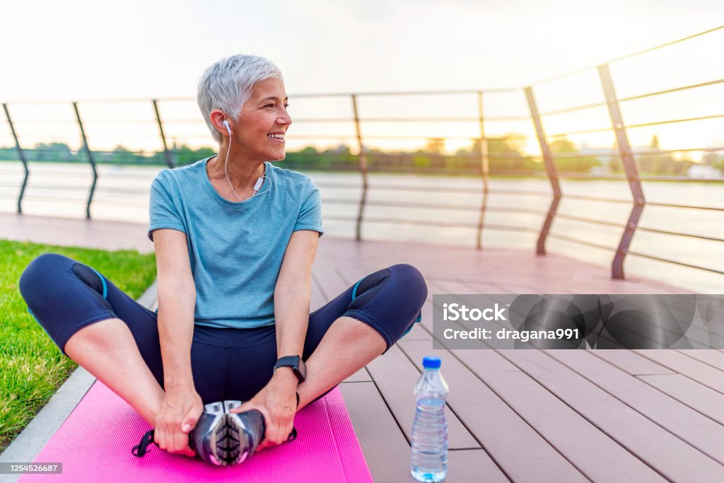 Mujer en una estera de yoga para relajarse al aire libre. - Foto de stock de Estilo de vida saludable libre de derechos