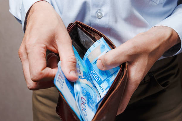 istock Man standing holding brown wallet with stack of money. Two thousandths Russian banknotes 1254528447
