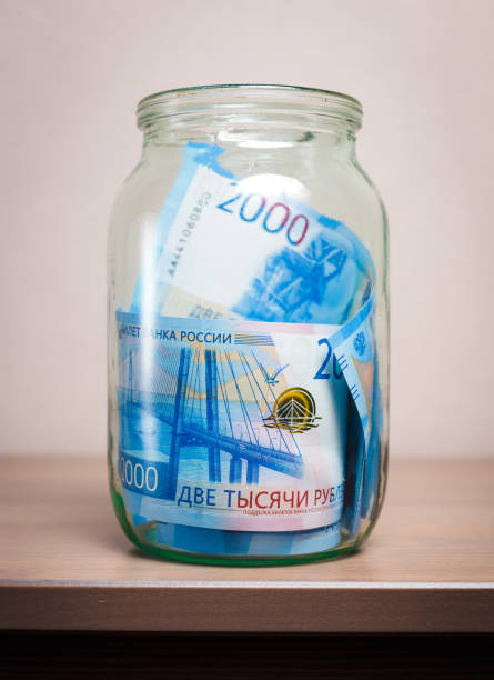 Glass jar with money on a human hand. Two thousandths Russian banknotes.