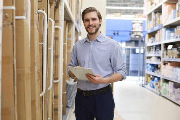 istock Young man shopping or working in a hardware warehouse standing checking supplies on his tablet. 1254529440