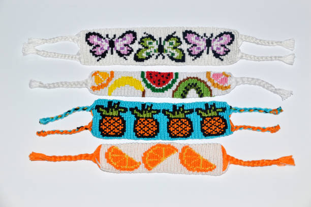 istock Woven friendship bracelets with alpha pattern fruit and butterflies handmade of thread on white background 1254529570