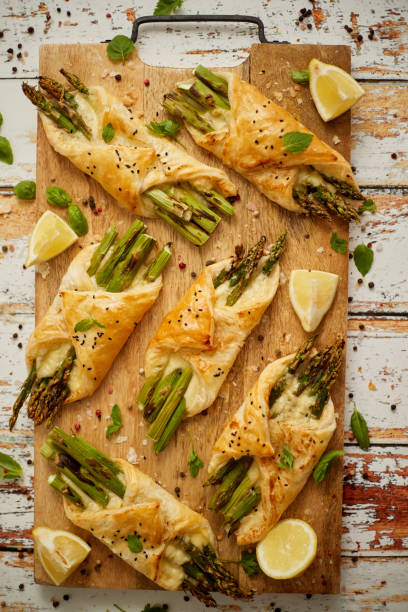 Grilled green asparagus and cheese puff pastry folded as envelope and topped with black sesame stock photo