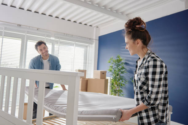 Couple putting comfortable mattress on big bed