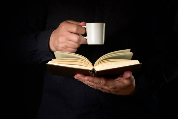 Reading on holidays. Coffee cup and books on table outdoors against blue sea water background. Book pages fluttering in the wind.