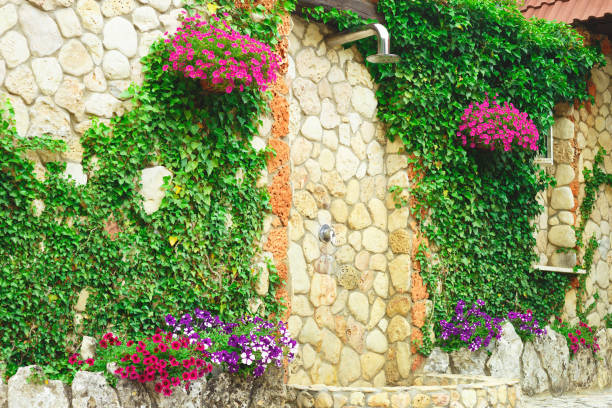 stone outdoor shower surrounded by greenery and flowers.
