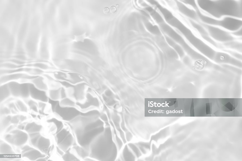 desaturated transparent clear calm water surface texture Closeup of desaturated transparent clear calm water surface texture with splashes and bubbles. Trendy abstract nature background. White-grey water waves in sunlight. Water Stock Photo