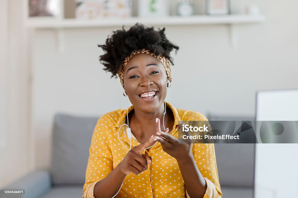 Technology makes connecting with the outside world so much easier Pretty African American Woman Looking at Camera and Taking Part Video call Involved in Virtual Conferencing With Colleagues During Video Conference in the Office Talking Stock Photo