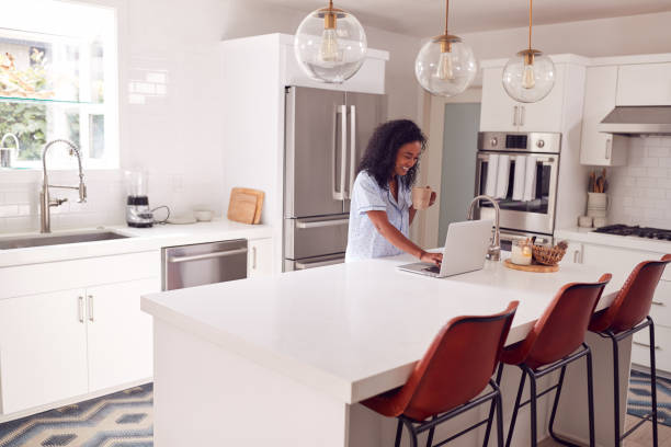 istock Woman Wearing Pyjamas Standing In Kitchen Working From Home On Laptop 1254537022