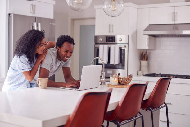 istock Couple Wearing Pyjamas Standing In Kitchen Working From Home On Laptop 1254537236
