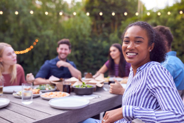 ritratto di amici multiculturali a casa seduti a tavola che si godono la festa in giardino estivo - festa in giardino foto e immagini stock