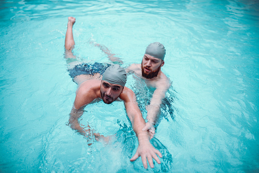 Male Teaching His Friend How To Swim