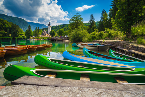Colorful canoes, kayaks and wooden rowing boats on the lake. Recreation and sport objects on the lake Bohinj, Ribcev Laz, Slovenia, Europe