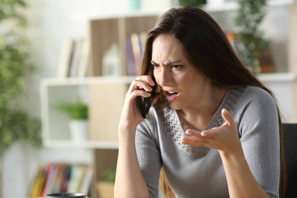 femme fâché appelant argumentant au téléphone à la maison - irritation photos et images de collection