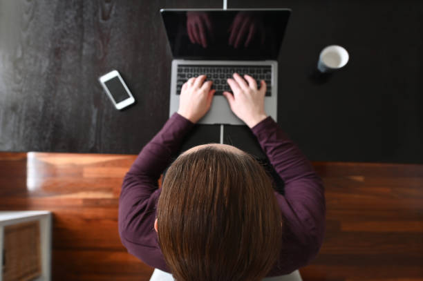 istock Above view of woman using a laptop on a desk  working from home 1254542012