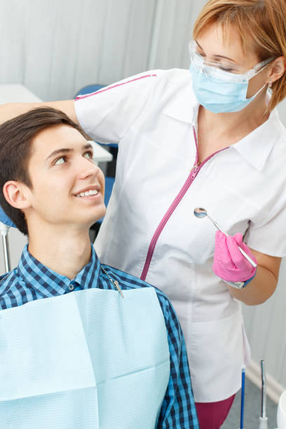 istock Female dentist and young man in dentist office 1254543777