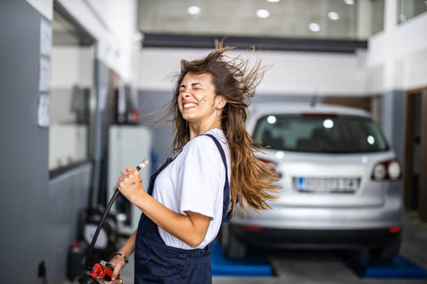 Female mechanic having fun with air pump in auto repair shop.