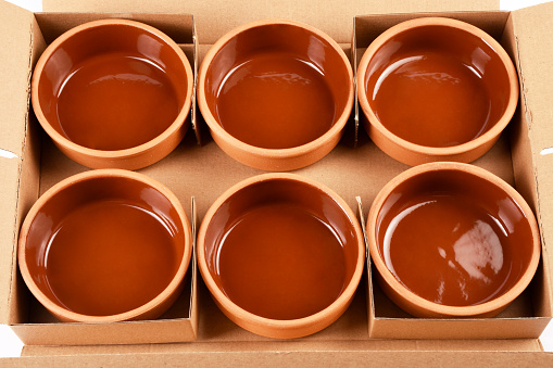 High angle view empty brown ceramic pots, stew bowls in a cardboard box