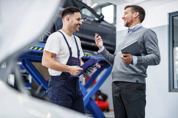 szczęśliwy mechanik samochodowy i jego menedżer rozmawiają w warsztacie naprawczym. - auto repair shop customer auto mechanic mechanic zdjęcia i obrazy z banku zdjęć