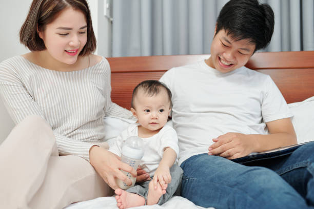 istock Parents and baby sitting in bed 1254549318