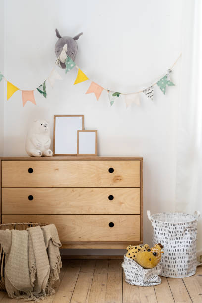 Cozy child bedroom with authentic interior design Vertical photo of cozy child bedroom with authentic interior design, flags on wall, home decor in wicker basket, toys on wooden chest of drawers nursery bedroom stock pictures, royalty-free photos & images