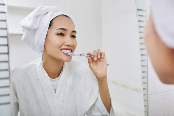 istock Young woman brushing teeth 1254553137