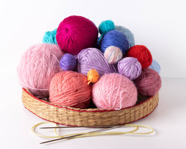 istock Balls of multi-colored threads for knitting in a wicker stand on a light background. Knitting needles. 1254558112