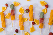 orange sorbet with ice , slices of orange and strawberries on white background.