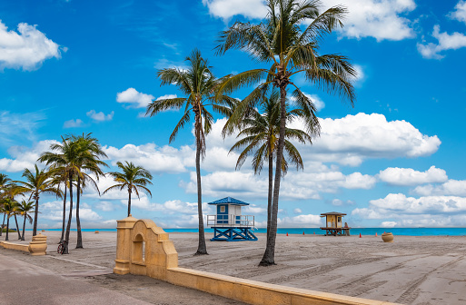 Colorful image with tropical beach and palm trees, lifeguard towers and boardwalk at the beach of Hollywood Florida, between Fort Lauderdale and Miami Beach, USA.