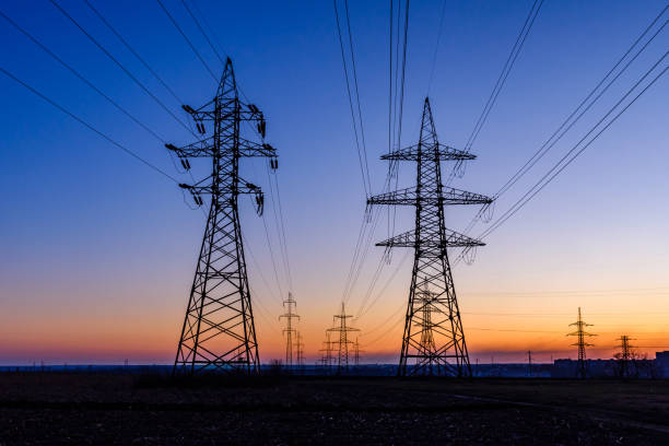 High voltage power line in a field at sunset stock photo