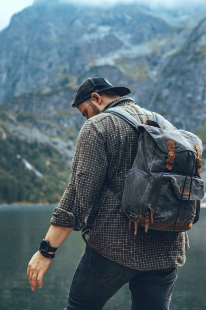 istock man with backpack at lake in mountains hiking concept 1254561698
