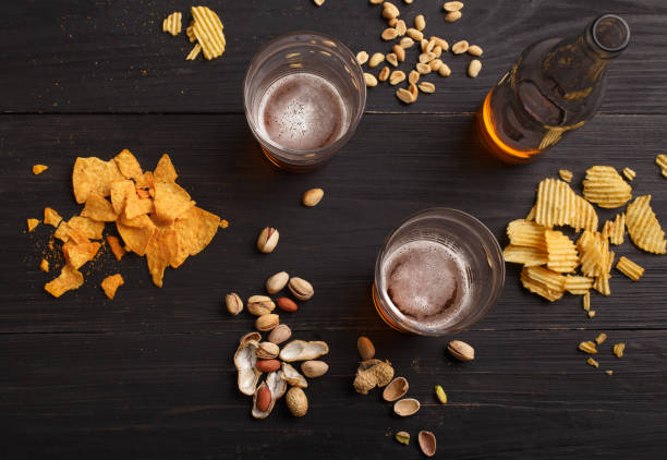 lager and snack. beer in bottles and glasses, chips, nuts and pistachios - beer nuts imagens e fotografias de stock