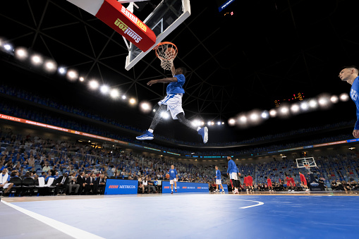 Low angle view of basketball player scoring slam dunk during the match.