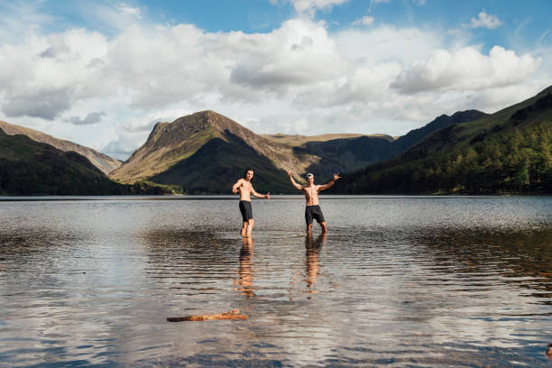 Male friends exploring the Lake district. They are wearing casual clothing and backpacks, hiking together in a scenic location.