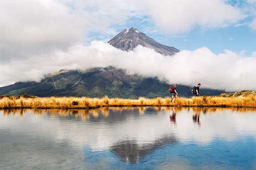 Hiker Heterosexual couple Reflection of Mount Taranaki Egmont in natural lake