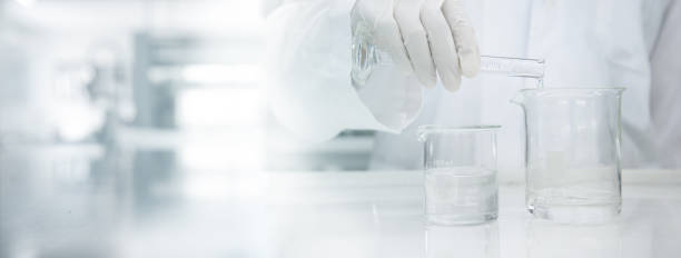 医学研究所の科学の背景にガラスビーカーに水をポーリング白衣の科学者 - stem glass ストックフォトと画像