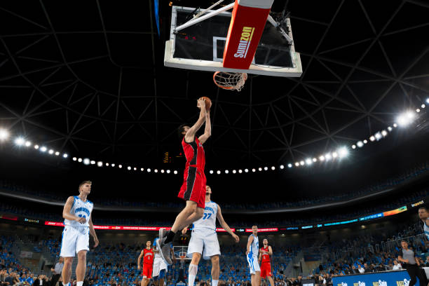 istock Basketball player slam dunking ball 1254565441