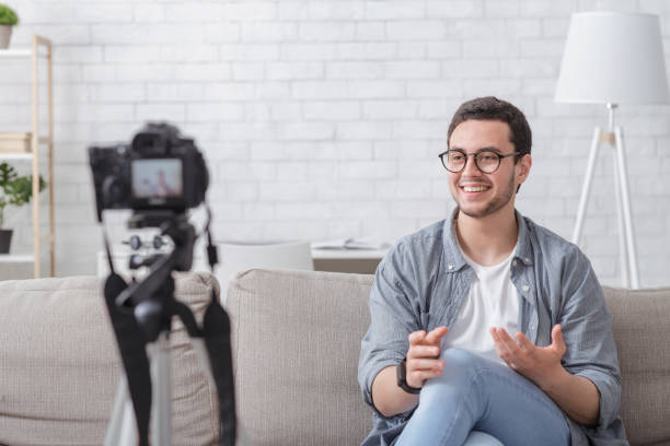 istock Marketing, e-commerce and video blogging. Smiling guy makes video with camera 1254565482