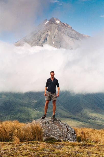 istock Man standing on rock infront of Mount Taranaki Egmont 1254565538